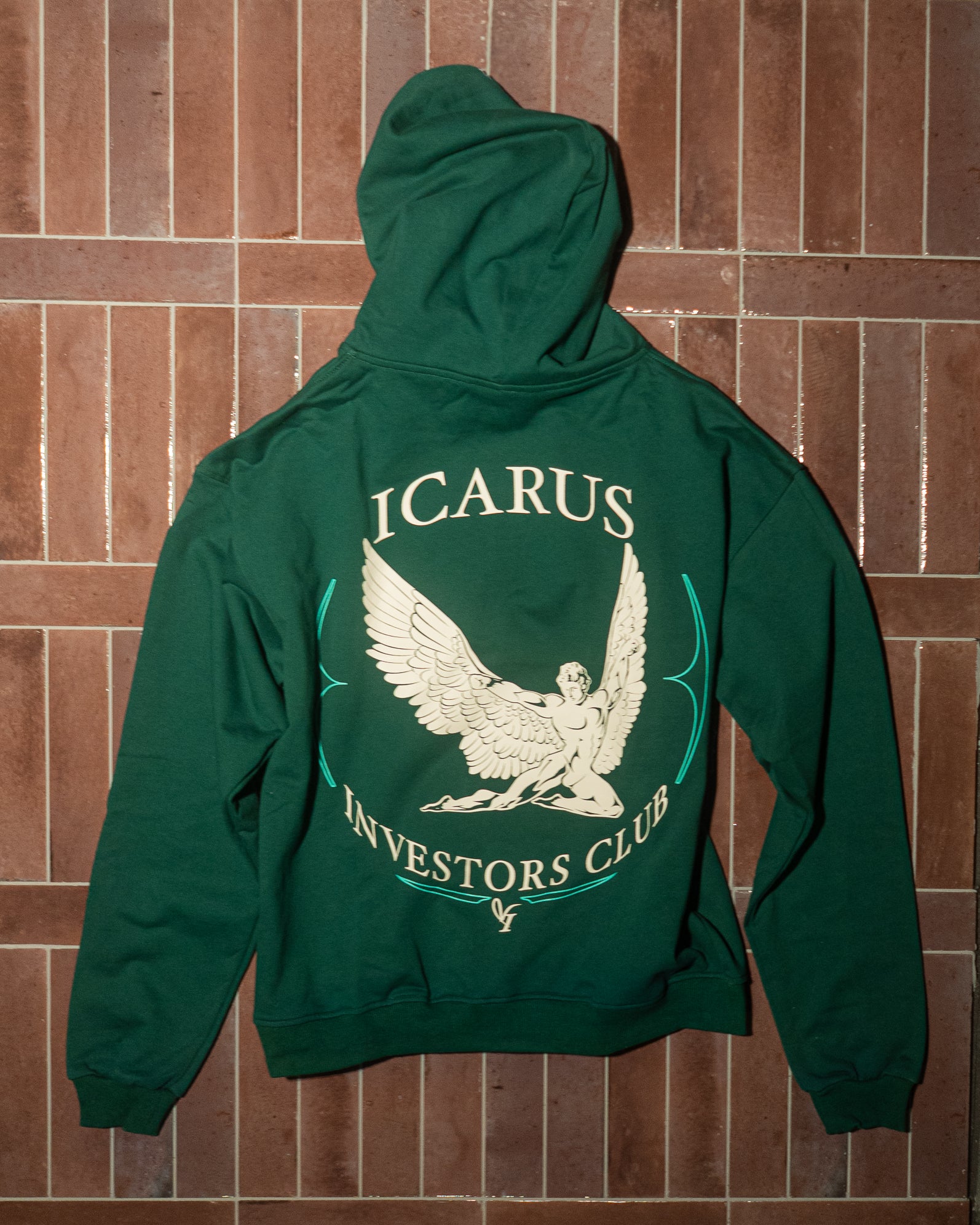 Green hoodie with 'Icarus Investors Club' design on a brick wall background